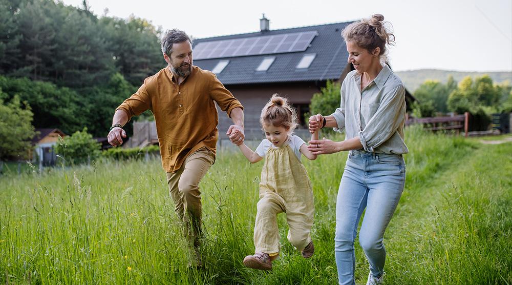 Blij gezin in het gras voor hun huis dat draait op duurzame energie