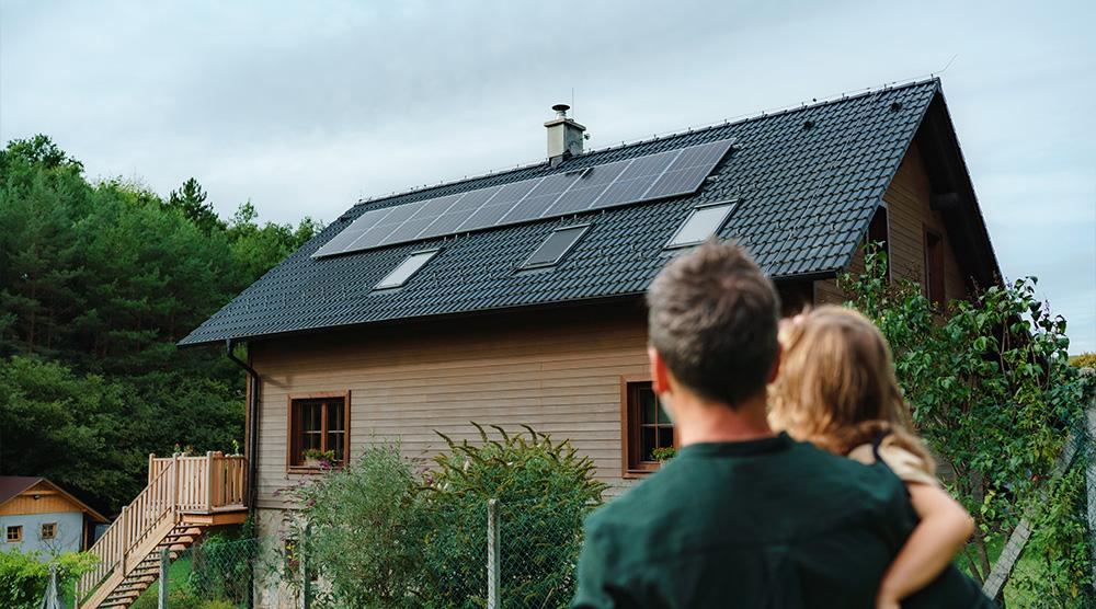 Jong gezin bewonderd de nieuwe zonnepanelen installatie op hun schuindak