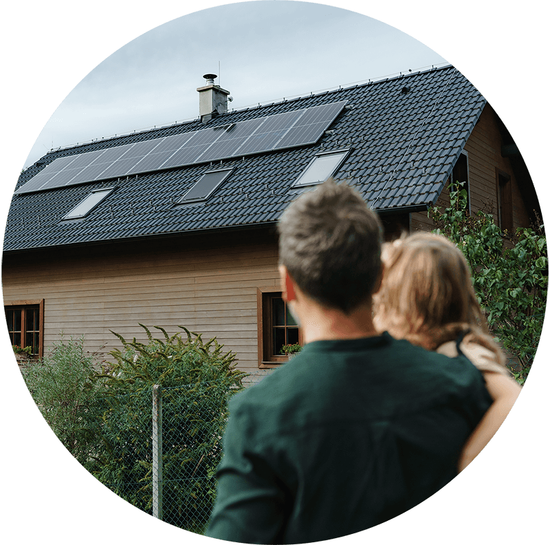 zonnepanelen op een dak, vader met dochter op de schouder kijken ernaar.